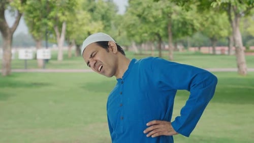 Muslim man suffering from back pain in park