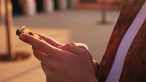 Person Using Mobile Phone in Golden Hour Light