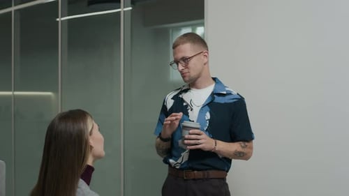 Office Colleagues Chatting during Coffee Break in Hallway