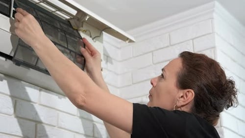Woman Changes Air Conditioner Filter at Home