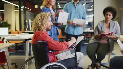 Happy disabled and diverse business people discussing work at office