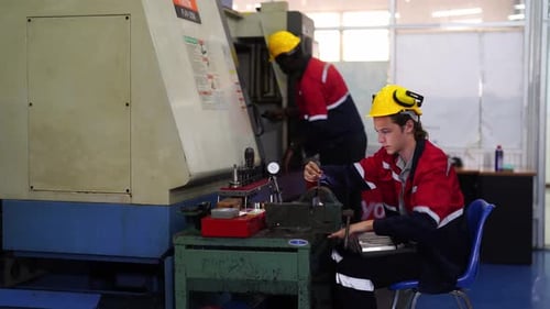 Workers working on the machine. metallurgy employees examining a piece of metal drill in a facility.