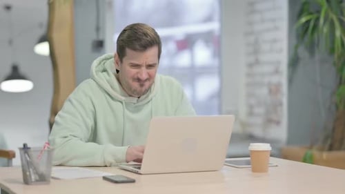 Young Man Reacting to Loss While Working in Office
