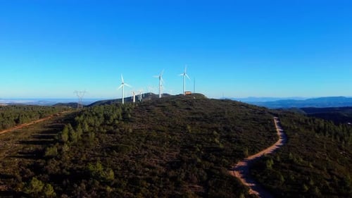 Aerial drone footage of a wind turbines on mountain ridges generating renewable energy.