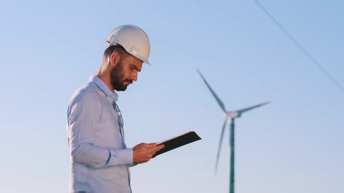 Reading the documents. Service engineer is on the field with windmillsReading the documents. Service