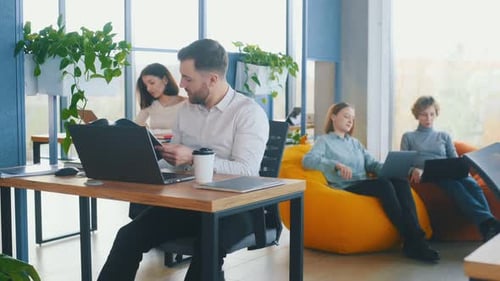 People are working in the office with bean bags chairs in it.