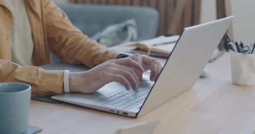 Closeup of Male Hands Typing with Laptop While Man Freelancer Using Computer at Desk at Home