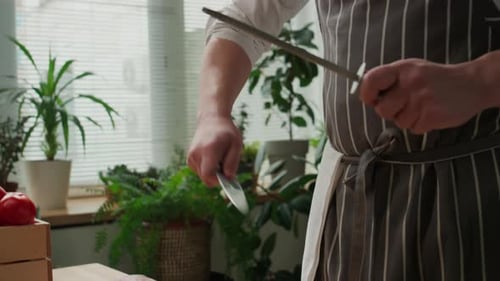 Person Sharpening Knife in Bright Kitchen