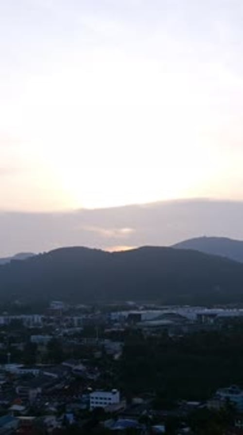 Coucher de soleil sur les toits de Mountain Town, voyagez dans un ciel pastel doux avec une lueur ambrée alors que le soleil se couche derrière la crête