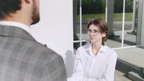 Conversation Between Two Smoking Professionals Outside a Modern Office Building During the Daytime