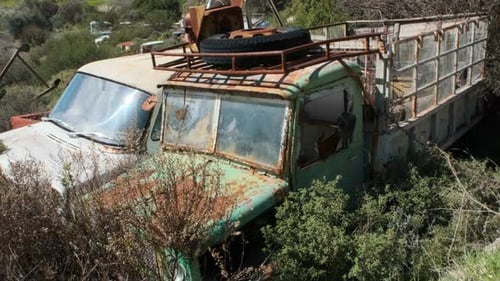 View of a vintage green truck in a car junkyard.