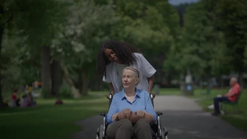 A Heartwarming Caring Moment in a Green Park Elderly Woman Enjoying Time in Wheelchair