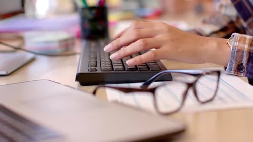 Hände einer gemischtrassigen Kreativen mit Computertastatur im ungezwungenen Büro, Zeitlupe