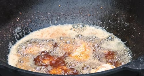 A Cauldron of Hot Oil is Used for Frying Fresh Juicy Chicken Legs in Breading