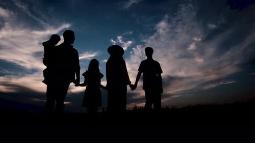 Una familia en el fondo de la puesta de sol camina cogida de la mano
