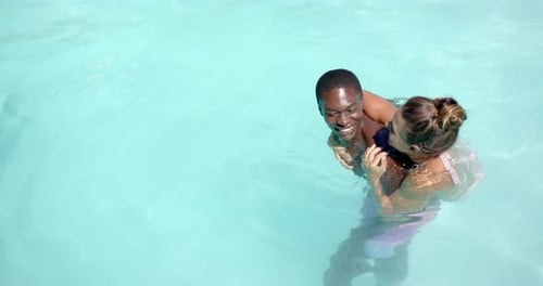 Enjoying summer vacation, happy diverse couple swimming in pool together, copy space