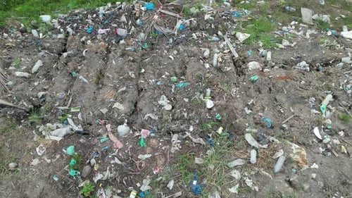 A pile of trash sitting on top of a dirt field