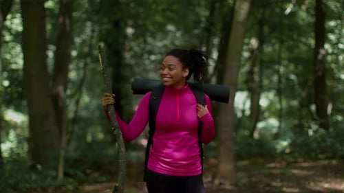 Happy Young African American Woman Explorer with Backpack Standing in Forest Enjoying Nature Around