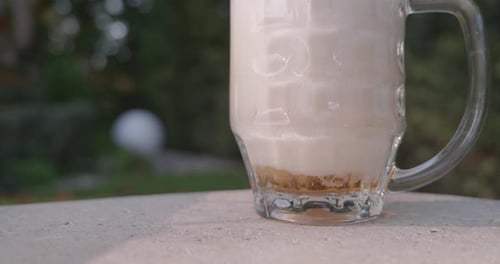 Foamy Beer Pours into Glass Mug Outdoors