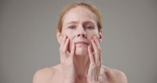 Mature Woman Gently Touching Face in Studio
