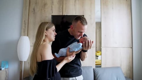 Loving parents holding their adorable newborn. Father waves a tiny son touching him nose to nose.