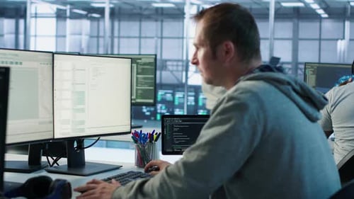 IT Programmer Arriving at Work in Data Center Sitting at PC Desk
