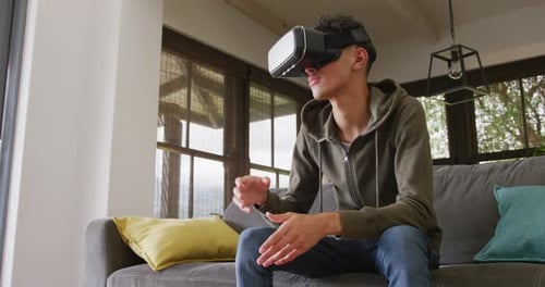 Biracial male teenage boy using vr headset at home, slow motion