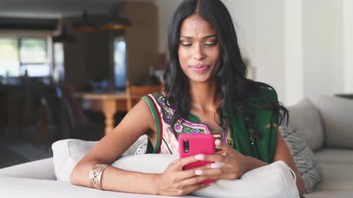 Smiling Woman Relaxing with Mobile Device on Couch