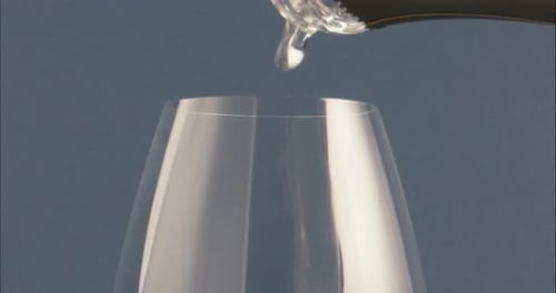 Pouring fresh clean water from a bottle into a transparent glass. detail shot.