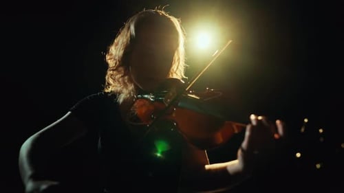 Violinist Playing Violin on Stage in Dark Setting