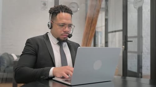 Multiracial Businessman with Headset in Call Center Typing on Laptop