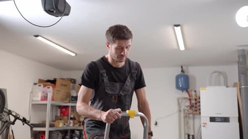 Man on Ladder Using Drill in Garage