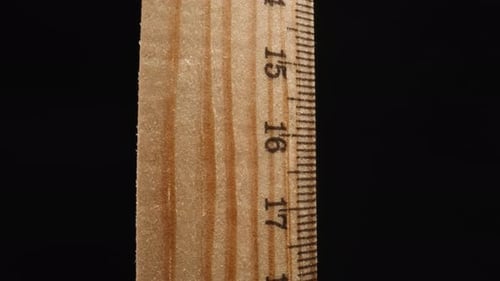 Lineal aus Holz mit Ziffern, die sich drehen, auf schwarzem Hintergrund