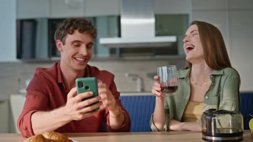 Young Couple Enjoying Coffee, Looking at Mobile Phone