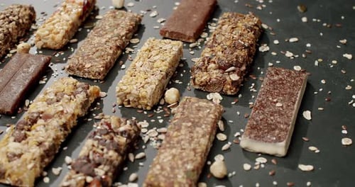 Assorted Granola and Protein Bars on a Dark Background with Scattered Oats