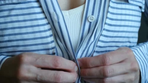Buttoning a Blue and White Striped Shirt Close Up