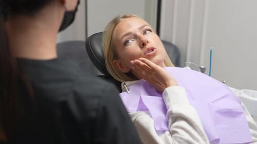 Closeup View From Unrecognizable Dentist Shoulder to Female Patient with Toothache Holding Hand on