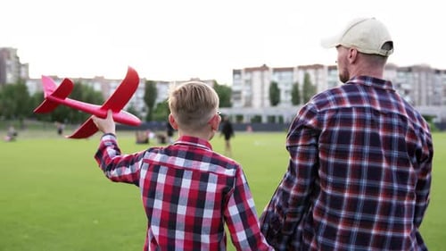 Father and child play with airplane at sunset in park. Happy family dream of becoming a pilot.