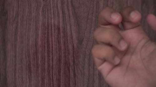 a person’s hand knocking on a wooden door, emphasizing texture, sound