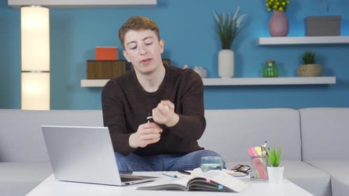 Young Adult Working on Laptop at Home Takes Medicine