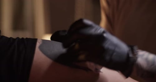 Tattoo Artist Wipes Ink from Arm Close Up