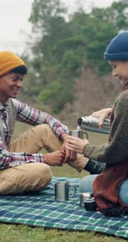 Friends Enjoying Thermos Drinks During Lakeside Picnic