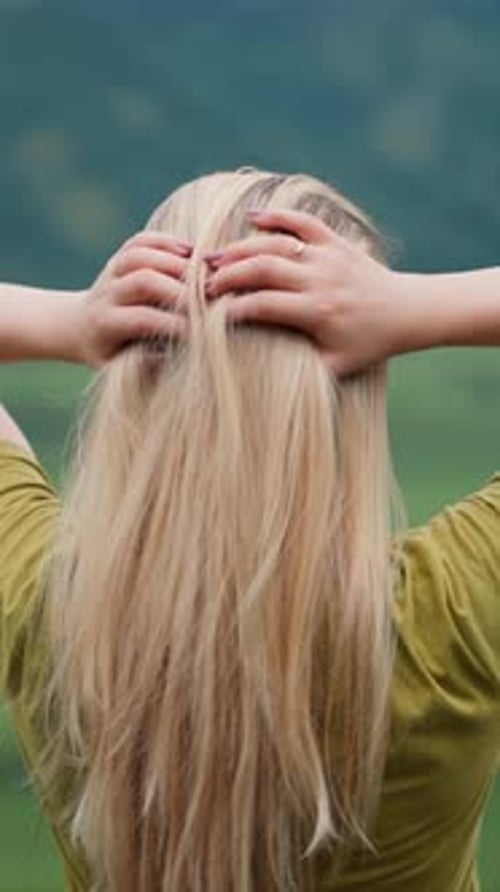 Lady Traveler Adjusts Long Hair Standing at Mountain Valley