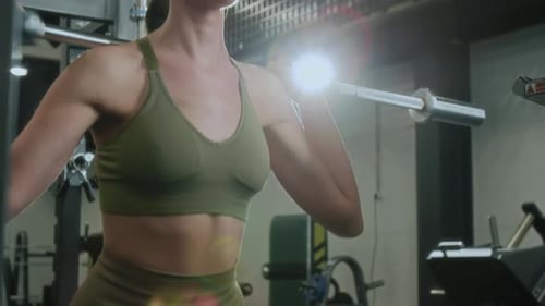 Fit Woman Doing Squats with Barbell on Shoulders while Exercising in Gym