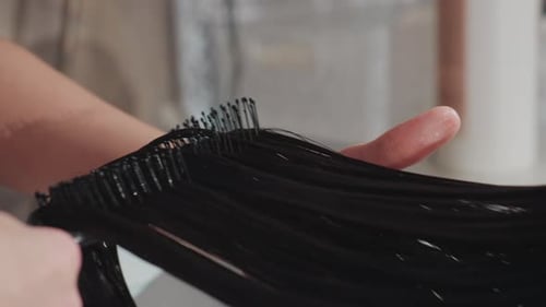 Caucasian Stylist Combing and Brushing Wet Hair Over Basin Closeup on Hands Brush and Glossy Strands
