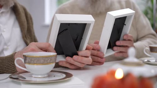 Seniors Holding Picture Frames at Table Indoors