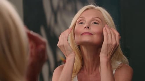 Woman Massaging Face and Neck in Mirror