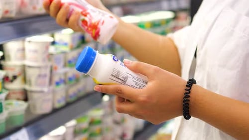 Young Woman Choosing Dairy Products in a Supermarket