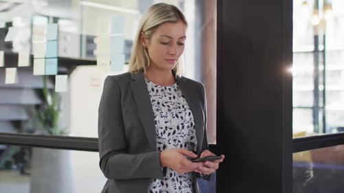 Portrait of caucasian businesswoman using smartphone smiling looking at camera