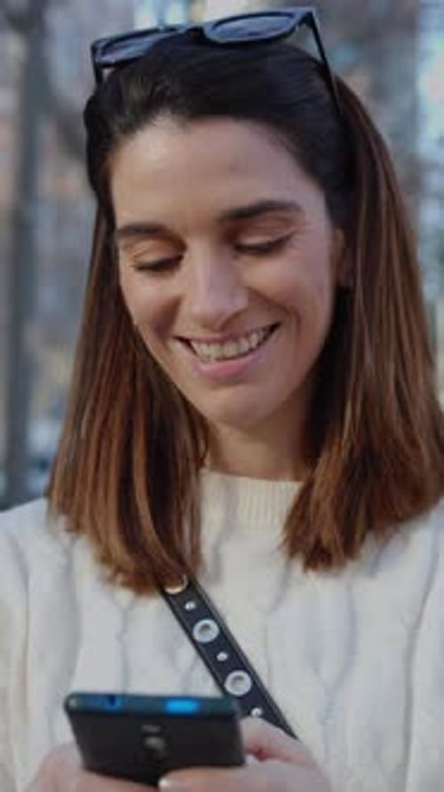 Beautiful Young Adult Woman Using a Smartphone Device at City Street